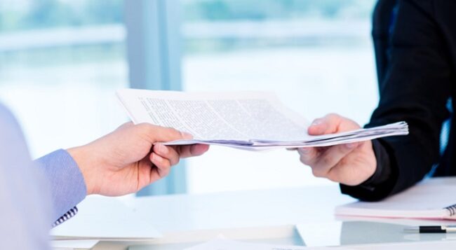 Business worker passing a pile of documents to his colleague