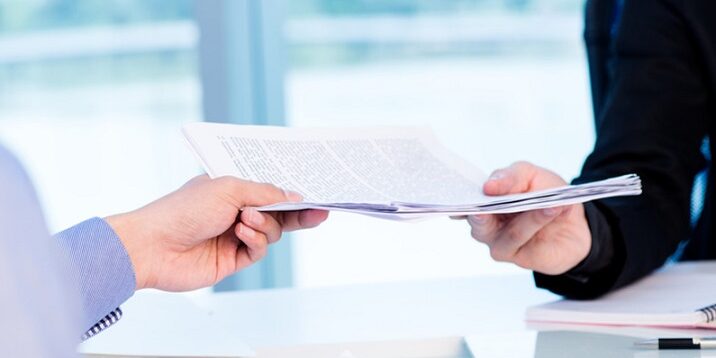 Business worker passing a pile of documents to his colleague